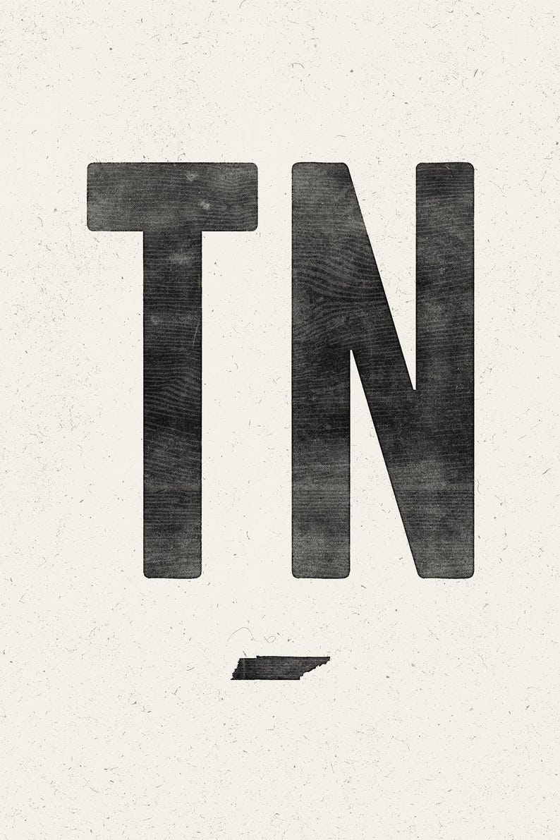 Pu&ograve; includere: Una stampa grafica che presenta le grandi lettere nere TN con una texture venata del legno. Sotto le lettere si trova una piccola silhouette nera solida dello stato del Tennessee, il tutto su uno sfondo testurizzato color bianco sporco.
