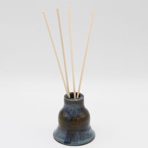 May include: A blue and brown ceramic diffuser bottle with wooden sticks.