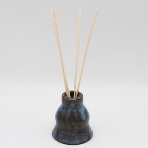 May include: A blue and brown ceramic diffuser bottle with wooden sticks.