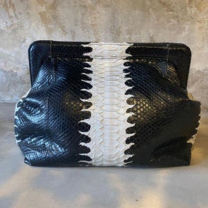 May include: A black and white snakeskin clutch purse with a textured design.