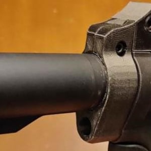 Puede incluir: Primer plano de un arma de fuego de metal negro con un cañón y una culata. El cañón tiene un extremo roscado y un anillo de metal negro alrededor.