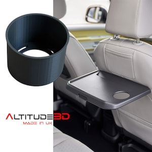 May include: A dark grey, cylindrical car cup holder and a grey car seat tray with a cup holder. The cup holder is 3D printed. The text "ALTITUDE 3D MADE IN UK" is visible.