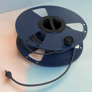 May include: A dark blue spool of wire with a black centre and a black knob. The wire is grey and extends from the spool, ending in a connector. The spool has a perforated design.