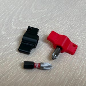 以下が含まれることがあります： 異なるハンドルを持つ3つのドライバービット。1つはT字型のハンドルが付いた黒色、もう1つはT字型のハンドルが付いた赤色、もう1つは小さなストレートハンドルが付いた黒色です。