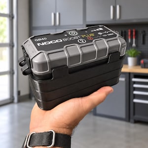 May include: A grey and black NOCO Boost Plus GB40 portable jump starter device featuring a rectangular shape with a rugged, textured casing, a power button, LED indicator lights, and printed text including 12V 1000A specifications.