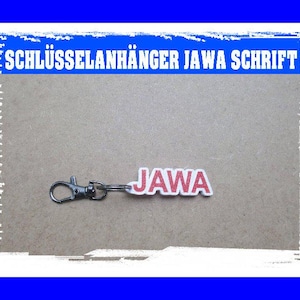 Könnte beinhalten: Ein silberner Schlüsselanhänger mit einem roten und weißen Stoffanhänger, auf dem in fetter Schrift "JAWA" steht.