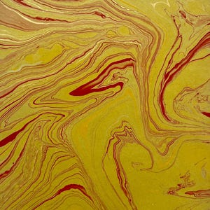 May include: A sheet of paper featuring a marbled pattern with swirling liquid colours. The design consists of vibrant mustard yellow, deep crimson red, and subtle cream-coloured veins that flow across the surface in organic, fluid, and wavy lines.