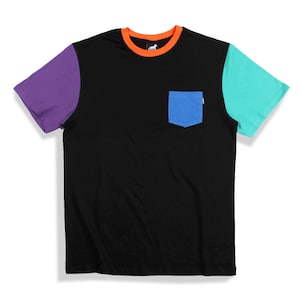 Pode incluir: Camiseta preta com bolso azul e mangas coloridas em roxo e verde-azulado. A gola redonda é laranja. Um pequeno logotipo de cavalo branco é visível na gola laranja.
