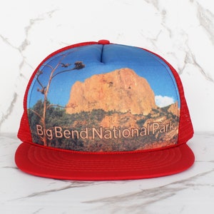 Op de afbeelding: Rode en blauwe truckercap met een foto van een bergketen en de tekst "Big Bend National Park".