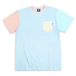 Pode incluir: Uma camiseta color block com corpo azul claro, manga esquerda cor de pêssego e manga direita azul claro. A camisa tem um bolso amarelo claro e uma gola rosa. Um pequeno logotipo é visível na gola e no bolso.