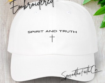 May include: White classic dad cap with the embroidered text "Spirit and Truth" and a cross symbol. The cap also features the word "Embroidered" and the signature "SpreadtheFaithCo."