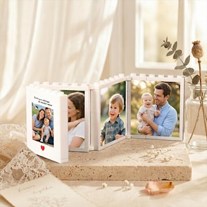 Könnte beinhalten: Ein modularer Bilderrahmen aus weißen Kunststoff-Klemmbausteinen mit vier verbundenen Paneelen. Jedes Paneel enthält ein Familienfoto, wobei auf dem ersten Rahmen der Text "Love you always, no matter what" und ein kleines rotes Herz aufgedruckt sind.