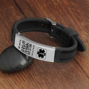 Op de afbeelding: Zwart siliconen armband met een zilveren metalen plaat waarop "HEALTH INFO" staat en een medisch symbool en een QR-code. Op de plaat staat ook "SCAN ME".