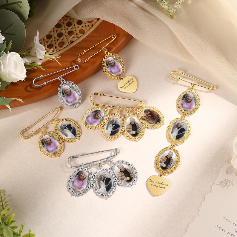 May include: A collection of memorial brooches with oval-shaped photo pendants. The brooches are in gold and silver tones, with decorative frames. Some have heart-shaped charms with the inscription "You are always in my heart."