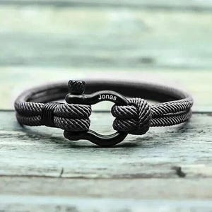 Peut inclure: Un bracelet en corde noire avec un fermoir en métal noir. Le fermoir porte le nom "Jonas" gravé.