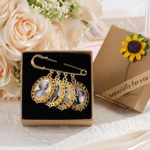May include: A gold-colored brooch with four oval-shaped pendants, each containing a black and white photograph. The brooch is displayed in a small box next to a gift box with a sunflower decoration and the text "especially for you".