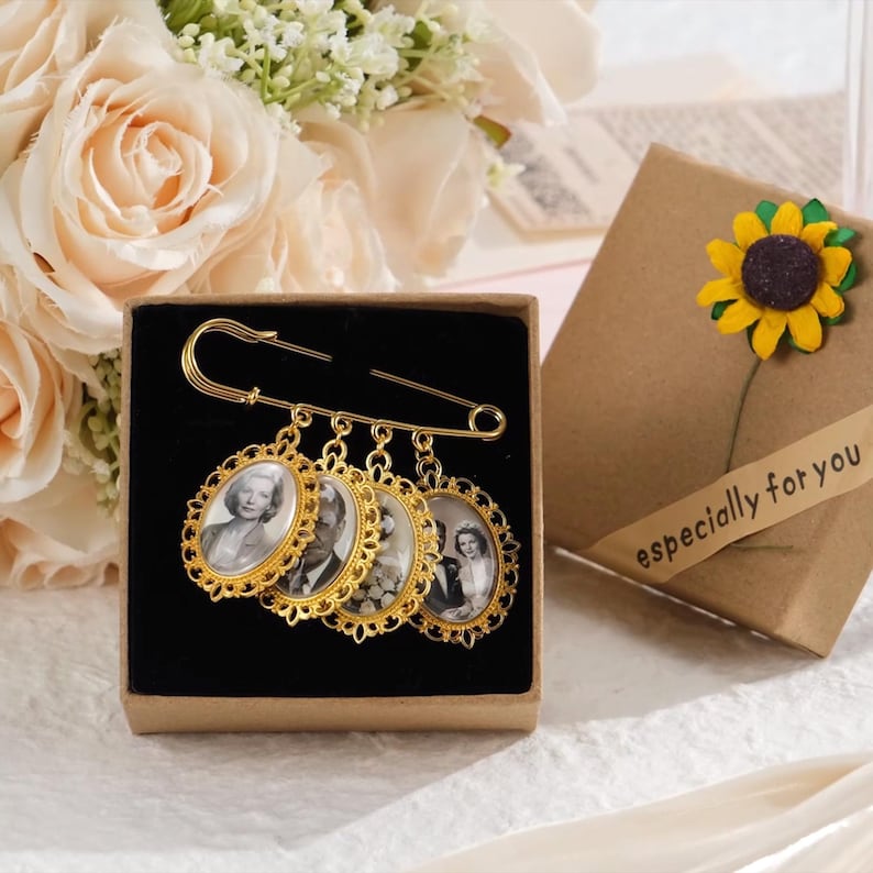 May include: A gold-colored brooch with four oval-shaped pendants, each containing a black and white photograph. The brooch is displayed in a small box next to a gift box with a sunflower decoration and the text "especially for you".