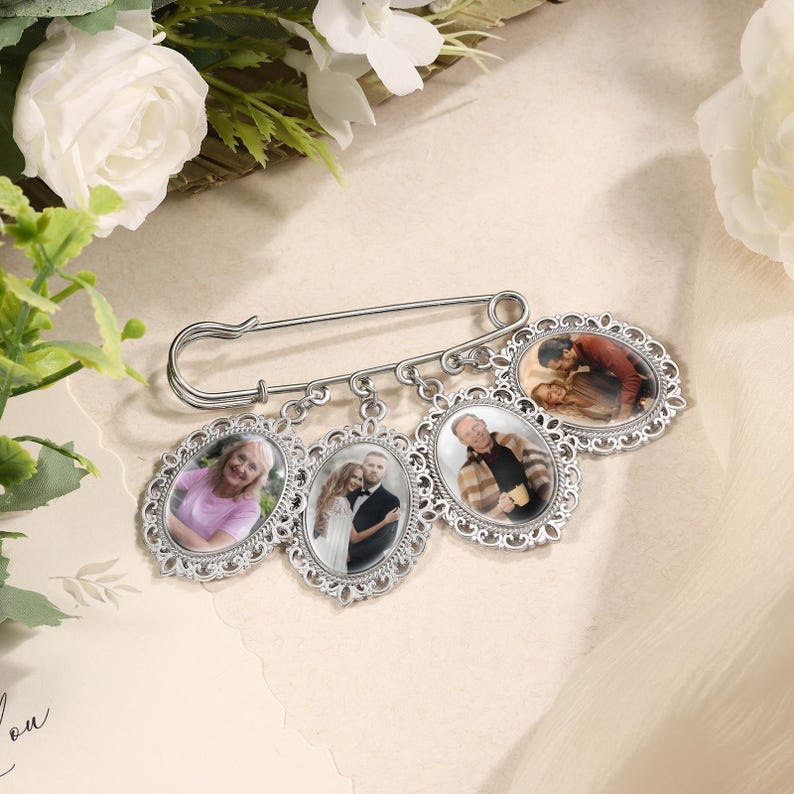 May include: A silver brooch pin with four oval photo frames. Each frame has a decorative edge and holds a different color photograph. The pin is a sentimental keepsake, perfect for displaying cherished memories.
