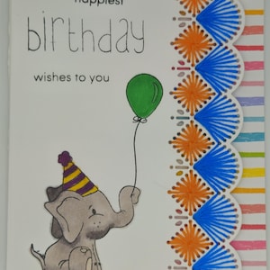 Könnte beinhalten: Eine weiße Grußkarte mit dem Text "happiest birthday wishes to you" und einem grauen Elefanten, der einen gelb-violetten Partyhut trägt und einen grünen Luftballon hält. Der rechte Rand hat eine Bogenkante mit orangefarbenem und blauem Garn.