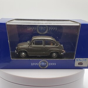 Può includere: Un modello di auto Fiat 500 verde degli anni '50 in una teca con il testo "1899 FIAT 1999" sul davanti e sul retro della teca.