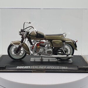 Może przedstawiać: Model motocykla Ducati Berliner Apollo 1963 w kolorze beżowym i czarnym w przezroczystej gablocie.