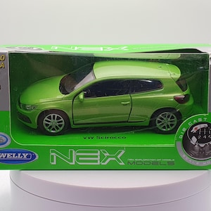 Puede incluir: Un modelo de coche de juguete de metal fundido a presión de color verde de un Volkswagen Scirocco en una caja verde y blanca. La caja tiene las palabras "Welly" y "Nex Models" en ella.