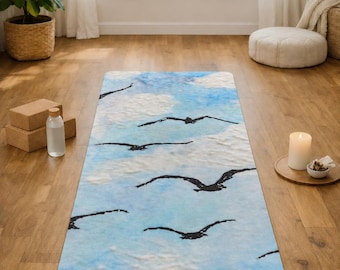 Puede incluir: Una esterilla de yoga rectangular con un patrón de cielo azul claro y blanco con siluetas negras de aves volando. El nombre Melissa está impreso en una fuente cursiva negra cerca del borde inferior de la esterilla, centrado en la superficie.