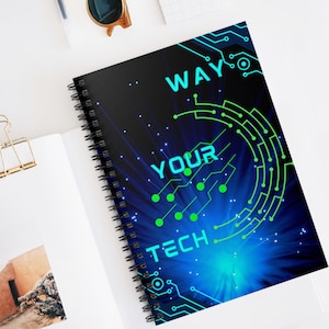 Op de afbeelding: Een zwart spiraalnotitieblok met een blauw en groen ontwerp. Het ontwerp bevat een cirkel met de woorden "Your Tech Way" in een groen lettertype.