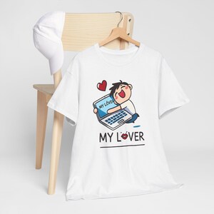 May include: White t-shirt with a cartoon illustration of a person holding a laptop with the text "My Lover" on the screen. The text "My Lover" is also printed below the illustration with a red heart.