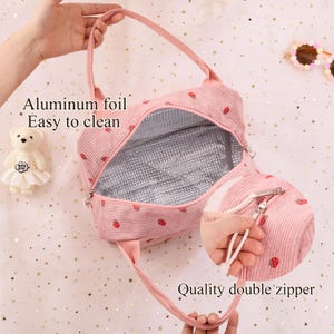 K&ouml;nnte beinhalten: Rosa Cord-Mittagessen-Tasche mit Erdbeermuster. Mit Aluminiumfolienfutter und einem hochwertigen Doppelrei&szlig;verschluss. Die Tasche hat einen Griff und den Text "Aluminum foil Easy to clean".