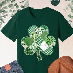 May include: A dark green t-shirt with a patchwork shamrock design in green and white. The image also shows blue jeans and a brown cowboy hat. The overall theme suggests a St. Patrick's Day celebration.
