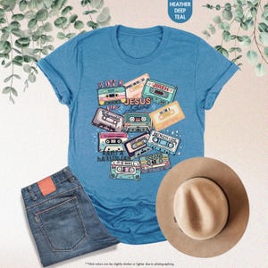 May include: A blue t-shirt with a graphic of vintage cassette tapes featuring Christian music lyrics like "He Knows My Name", "Waymaker", "Reckless Love", "Oceans", "It Is Well", and "Raise a Hallelujah".
