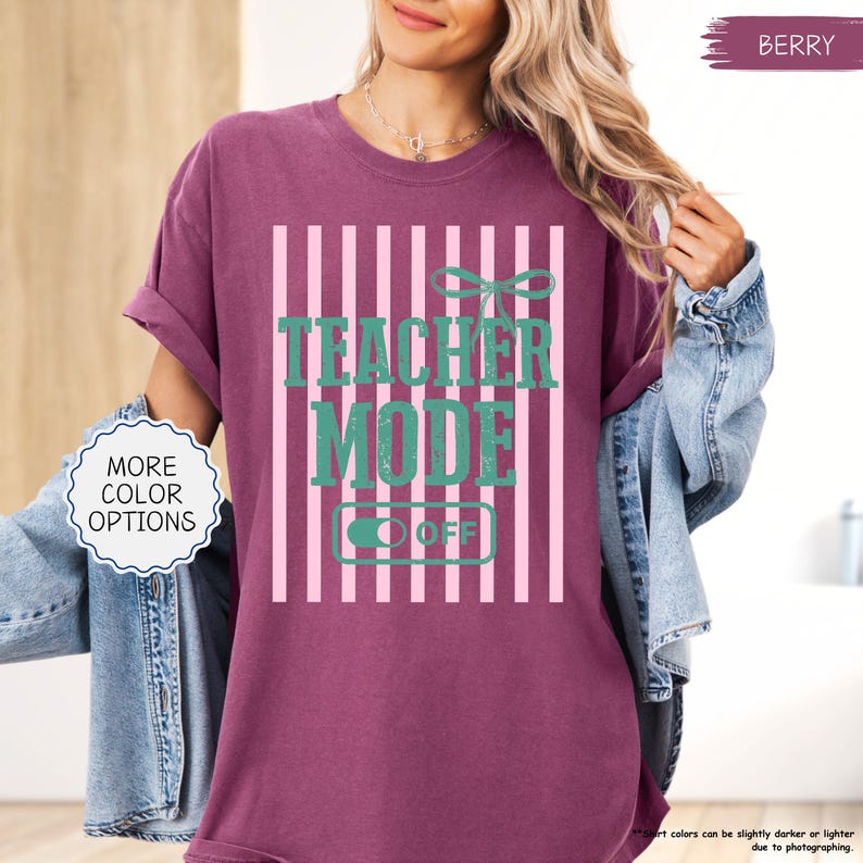 May include: Berry-colored t-shirt with the text "TEACHER MODE OFF" in teal. The design features a bow and vertical pink stripes. The shirt has rolled-up sleeves and is part of a clothing collection.