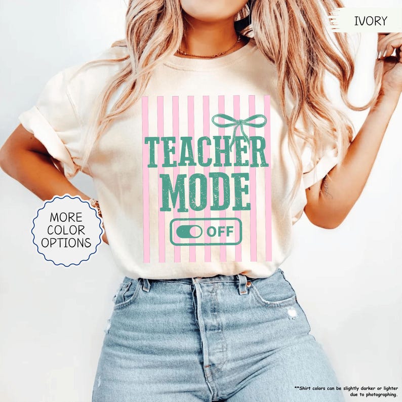 May include: Ivory-colored t-shirt with the text "TEACHER MODE OFF" in teal and pink. The design includes a pink and white striped background and a teal bow. The shirt also has a "MORE COLOR OPTIONS" button.