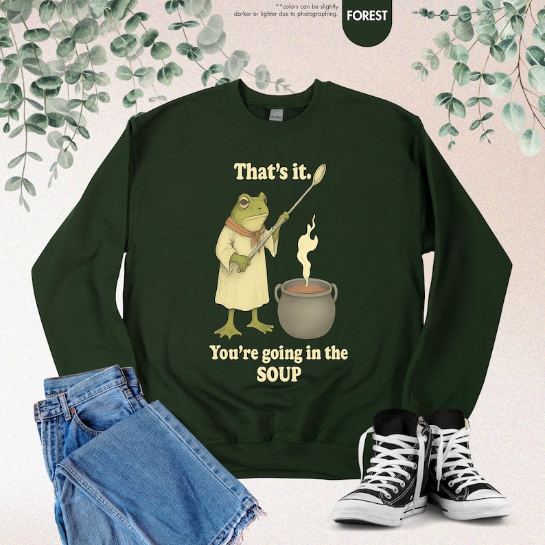 Pu&ograve; includere: Felpa verde foresta con una grafica di un ranocchio chef che tiene un cucchiaio sopra una pentola di zuppa. Il testo recita: "That's it. You're going in the SOUP."