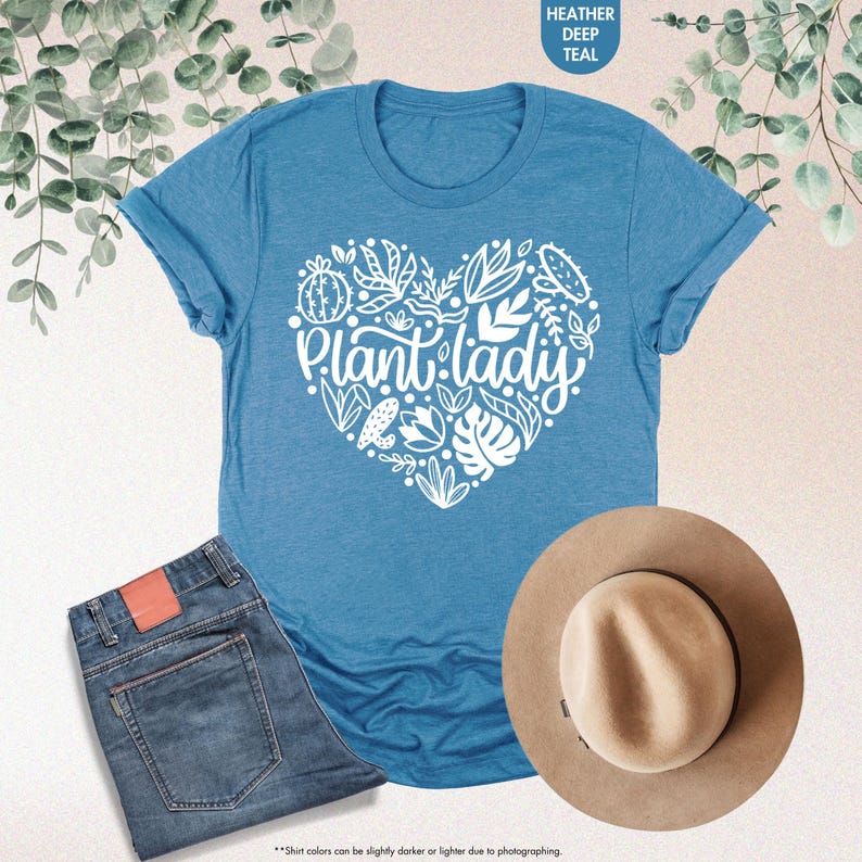 May include: A blue t-shirt with a white heart design that says "Plant lady". The heart is filled with various plant and flower illustrations.
