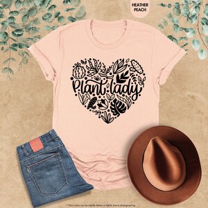 May include: A pink t-shirt with a black heart design featuring the text "Plant lady" surrounded by leaves and flowers.