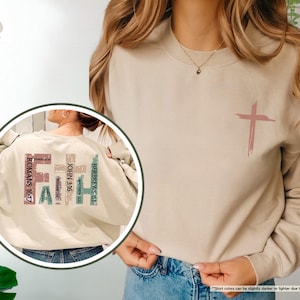 May include: A beige sweatshirt with a cross design on the front and the word "FAITH" spelled out vertically on the back with bible verses. The verses are: Hebrews 11:1, John 3:16, Matthew 17:20, Romans 10:17, Ephesians 2:8, and Mark 9:23.