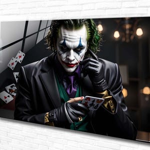 May include: A close-up portrait of the Joker, a fictional character from the Batman comics, with green hair, white face paint, and a red smile. He is wearing a black suit, a purple tie, and a green vest. He is holding a deck of playing cards in his hand and looking directly at the viewer.