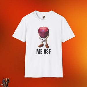 May include: White t-shirt with a red apple with a face and arms. The apple is holding its hands in front of it. The text "ME ASF" is printed below the apple.