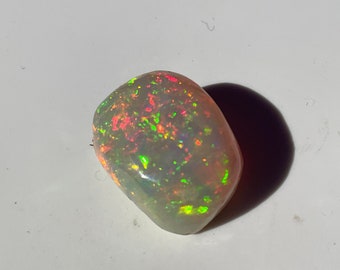 May include: A white opal gemstone with green, red, and orange flashes of color.