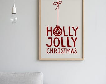 May include: A framed print with the words "HOLLY JOLLY CHRISTMAS" in red, with a decorative ornament and bow design. The print is in a light wood frame and hangs on a gray wall. A light bulb hangs from the ceiling.