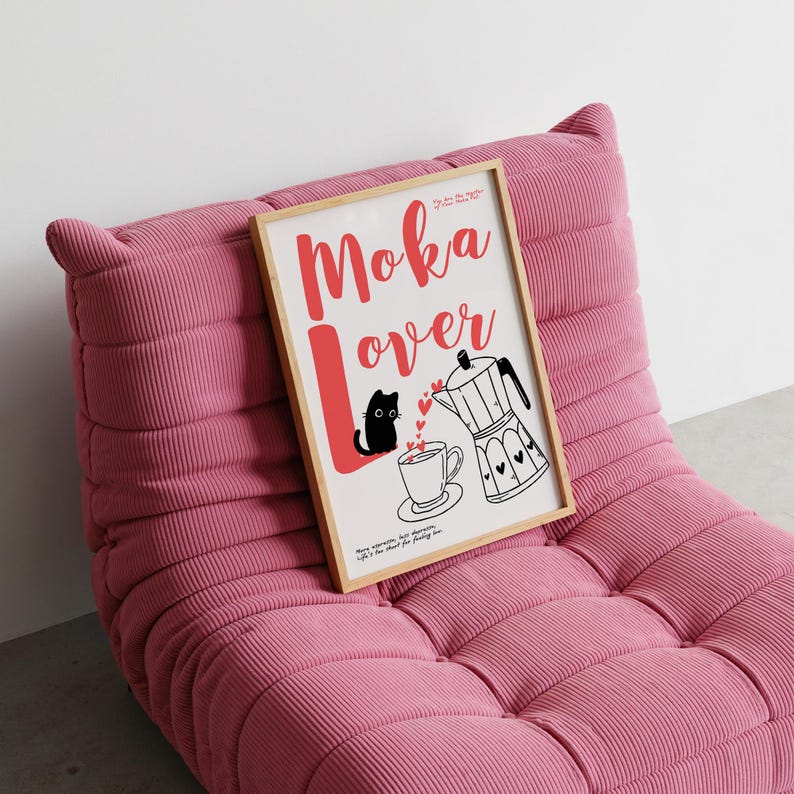 May include: A framed print with the words "Moka Lover" in red script, featuring a black cat, coffee cup, and a moka pot illustration. The print is displayed on a pink corduroy lounge chair.