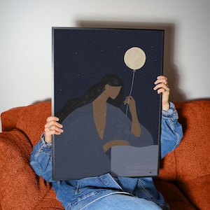 Könnte beinhalten: Ein gerahmter rechteckiger Kunstdruck mit einem dunkelblauen Nachthimmel voller kleiner Sterne. Eine Figur mit langem dunklem Haar trägt einen tiefblauen Morgenmantel und hält einen einzelnen blassgelben runden Luftballon.