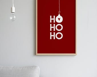 May include: A framed print with a red background features the words "HO HO HO" in white, with a heart-shaped ornament above the top "HO". The print is in a wooden frame, suitable for holiday decor.
