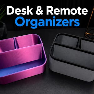 May include: Two rectangular desk and remote organizers with three internal compartments each. One organizer features a metallic purple and blue gradient finish, while the other is matte black and gray. The text Desk & Remote Organizers is visible.