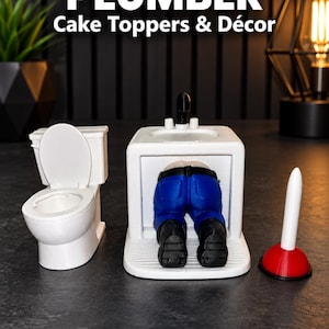 May include: A white toilet, a white sink unit with a figure wearing blue pants and black boots crawling underneath, and a red and white plunger. The text PLUMBER Cake Toppers & Décor is visible at the top of the image.