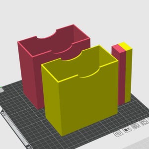 May include: A 3D digital rendering of two rectangular storage containers with open tops and semi-circular cutouts on the front edges. One container is dark pink and the other is yellow. A thin, matching pink and yellow divider stands nearby.