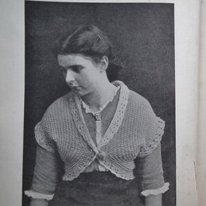May include: A black and white image of a woman wearing a knitted bolero. The bolero is light-colored with a decorative trim around the edges. The text at the bottom reads "Knitted Hug-Me-Tight or Bolero."