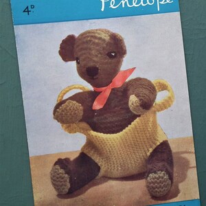 May include: A crochet pattern for a brown teddy bear with a yellow basket. The pattern is designed by Penelope and is made with Melody 3-ply wool. The pattern number is M1307.